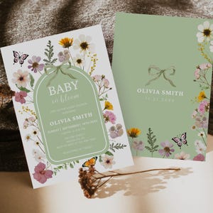 Puede incluir: Invitaciones para baby shower con diseños florales y mariposas. La invitación de la izquierda tiene el texto "Baby in Bloom" y los detalles del evento. La invitación de la derecha presenta un lazo y el nombre "Olivia Smith". La paleta de colores incluye verde, rosa y amarillo.