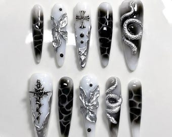 Gotische grunge-pers op nagels: zilveren slang, zwart kruis en chroombloem