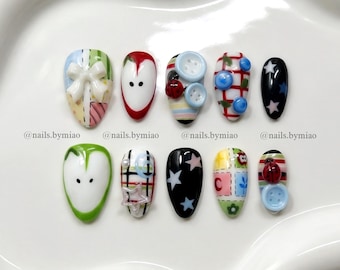 Uñas postizas coloridas con diseño de patchwork: botones 3D, estrellas, cintas y diseño de corazón de manzana.