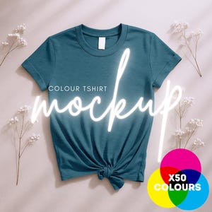 以下が含まれることがあります： 薄いベージュの表面に置かれた、ターコイズブルーのTシャツのモックアップ。Tシャツは前面で結ばれており、白い文字で「COLOUR TSHIRT mockup」と書いてあります。右下には「X50 COLOURS」という文字が入ったカラフルな円があります。