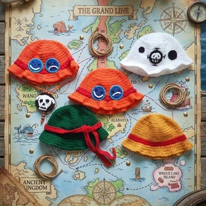 Könnte beinhalten: Fünf gehäkelte Fischerhüte in verschiedenen Farben und Designs, darunter orange mit blauer Brille, weiß mit schwarzem Totenkopf-Emblem, grün mit rotem Band und gelb mit rotem Streifen. Ein kleiner Totenkopf-Anhänger an einer Kordel ist dabei.
