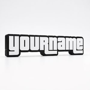 Puede incluir: Un letrero en blanco y negro con el texto "YOURname" en una fuente audaz y estilizada. Las letras son blancas con un contorno negro y un fondo negro. El letrero es rectangular y parece ser una placa de identificación o un letrero personalizado.