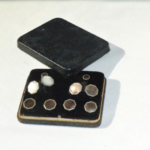 May include: A set of eight cufflinks in a black velvet lined box. The cufflinks are made of mother of pearl and have a silver tone finish.