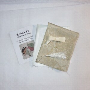 May include: A kit for making a Regency purse, containing fabric, a tassel, ribbon, and safety pins. The kit includes instructions with the text "Reticule Kit, Royal House of Whimsy, Everything you need to make your own Regency purse."