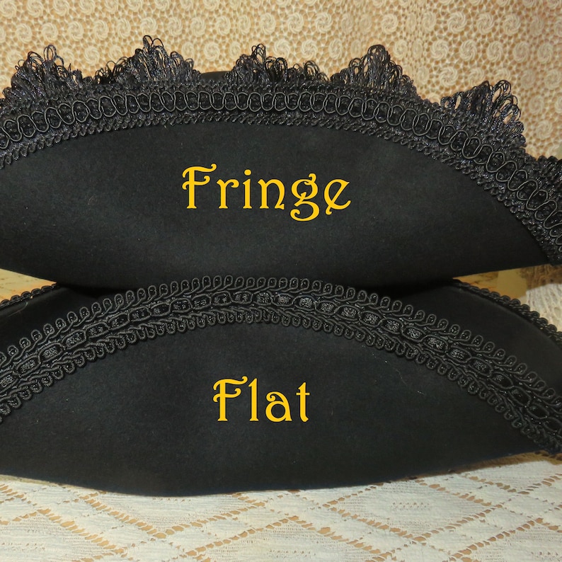 May include: Two black tricorn hats, one with a fringed edge and the other with a flat edge. Both hats are trimmed with black decorative trim. The word "Fringe" is written in yellow on the top hat, and "Flat" is written on the bottom hat.