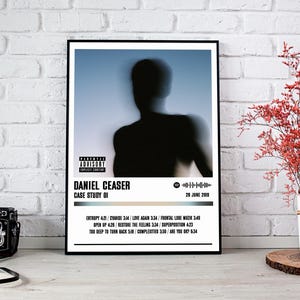 May include: Black framed poster featuring a blurred silhouette of a person against a blue background. The poster includes the text "DANIEL CEASER CASE STUDY 01" and a list of song titles with durations. A parental advisory warning is also present.