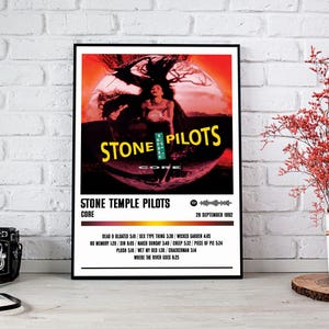 May include: A framed poster for Stone Temple Pilots' album "Core." The artwork shows a woman against a red and orange backdrop, with the band's name in yellow. The poster includes the album's tracklist and the date 29 September 1992.