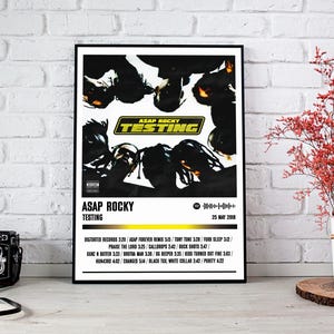 Puede incluir: Un póster en blanco y negro con un diseño minimalista que presenta a un grupo de personas en blanco y negro. El póster tiene el título "ASAP ROCKY TESTING" y la fecha "25 DE MAYO DE 2018". El póster también enumera los títulos de las pistas y las duraciones del álbum.