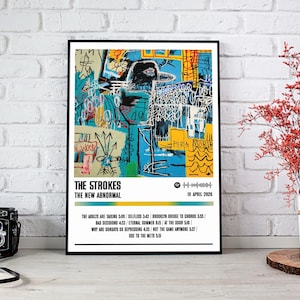 May include: A framed poster with abstract art in blue, yellow, and white. The poster has the text "THE STROKES THE NEW ABNORMAL" and a list of song titles. The date "10 APRIL 2020" is also visible.