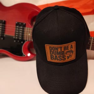 May include: Black baseball cap with a brown leather patch that says "Don't be a Dumb Bass" with a fish graphic.