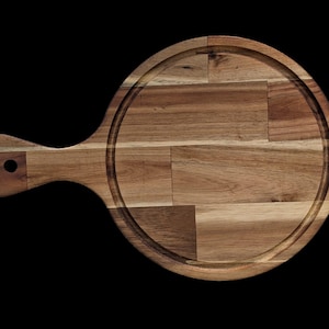 Puede incluir: Tabla redonda de madera para servir con asa. La tabla es de madera marrón claro y presenta una ranura circular alrededor del borde. El asa tiene un agujero para colgar. Ideal para servir aperitivos o platos pequeños.