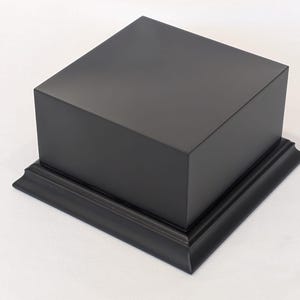 Peut inclure: Une tasse en céramique blanche avec une anse noire et le texte "But First, Coffee" en noir, en gras. La tasse est posée sur une surface en bois.