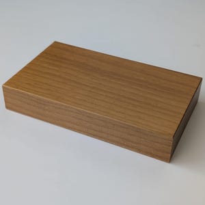 Puede incluir: Una caja de madera rectangular con un acabado de madera de grano marrón claro.