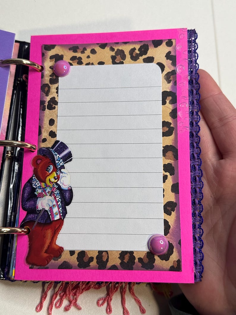 Puede incluir: Una p&aacute;gina de diario hecha a mano con un borde rosa brillante, fondo de estampado de leopardo y papel rayado. Un oso de dibujos animados con sombrero de copa y traje est&aacute; a la izquierda. Dos chinchetas rosas aseguran el papel. Ribete de encaje morado a la derecha.