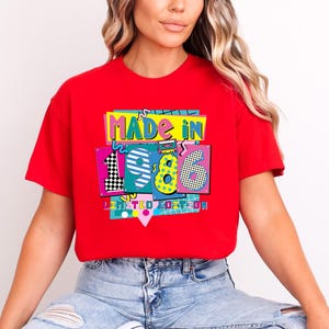 May include: A red t-shirt with a colorful graphic that says "MADE IN 1986 LIMITED EDITION." The graphic has a retro 80s design with the numbers 1, 9, 8, and 6 in different patterns and colors.