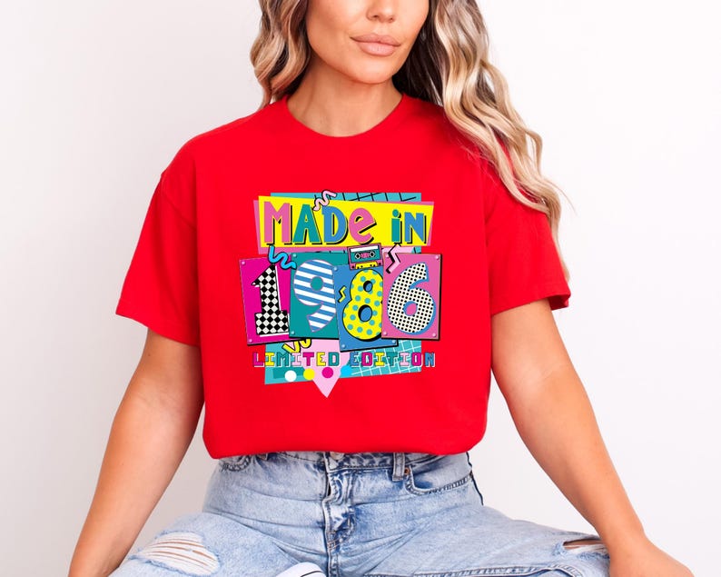 May include: A red t-shirt with a colorful graphic that says "MADE IN 1986 LIMITED EDITION." The graphic has a retro 80s design with the numbers 1, 9, 8, and 6 in different patterns and colors.