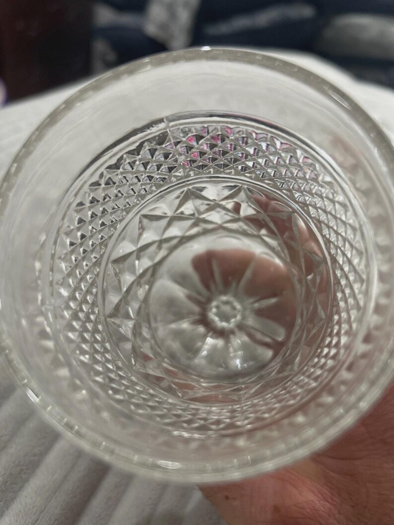 May include: Clear glass tumbler with a diamond pattern on the bottom and sides. The glass has a thick base and a smooth rim. The design is visible from the inside of the glass.
