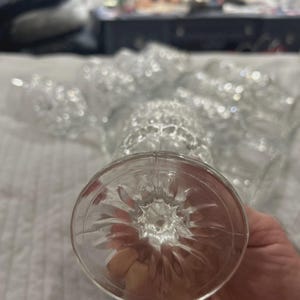 May include: Clear, stemmed glassware with a textured design. The base of the glass features a starburst pattern. Several glasses are visible, suggesting a set for beverages or formal occasions.