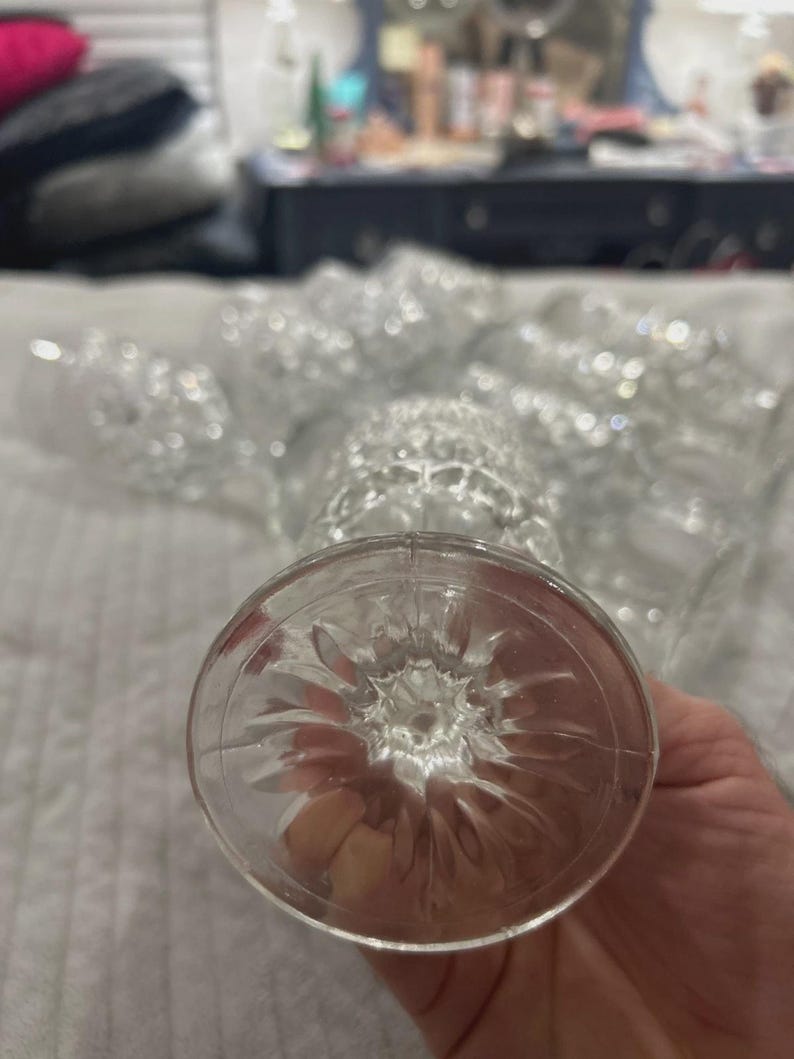 May include: Clear, stemmed glassware with a textured design. The base of the glass features a starburst pattern. Several glasses are visible, suggesting a set for beverages or formal occasions.