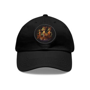 May include: Black baseball cap with a circular patch showing three dragon-like creatures in a boat. The creatures have green skin and orange clothing. The hat has a curved peak and an adjustable strap at the back.