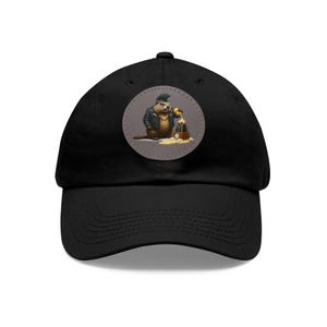 May include: A black baseball cap with a round patch featuring a cartoon beaver wearing a leather jacket and pouring a drink from a bottle into a glass.