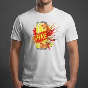 K&ouml;nnte beinhalten: Wei&szlig;es T-Shirt mit einem farbenfrohen Grafikdesign einer Getr&auml;nkedose. Das Design zeigt das Wort "FIRE" in fetten Buchstaben, Zitronen- und Orangenscheiben, Chilischoten und Ingwer, vor einem roten und gelben Hintergrund.