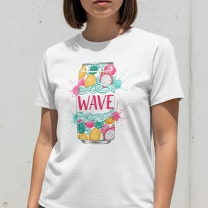 K&ouml;nnte beinhalten: Wei&szlig;es T-Shirt mit einer farbenfrohen Illustration einer Getr&auml;nkedose. Das Dosen-Design zeigt Ananas, Drachenfrucht und das Wort "WAVE" in Pink, mit blauen und rosa Aquarellspritzern.