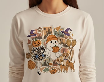May include: Cream-colored long-sleeve shirt featuring a collage of Halloween-themed illustrations. The design includes a pumpkin-headed figure, a ghost holding a pumpkin, witch hats, brooms, and dogs. The shirt is made of a soft, comfortable material.