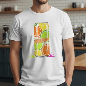 K&ouml;nnte beinhalten: Wei&szlig;es T-Shirt mit einem farbenfrohen Grafikdesign einer Getr&auml;nkedose. Das Dosen-Design zeigt Orangen-, Zitronen- und Limettenscheiben mit dem Wort "ENERGY". Gelbe und rosa Farbspritzer befinden sich am unteren Rand.