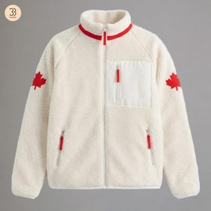 May include: Cream fleece jacket with a high collar and full-length zip. It has a white chest pocket and two side pockets, all with red zip pulls. Red maple leaf emblems are on the sleeves. A warm, comfortable outerwear item.