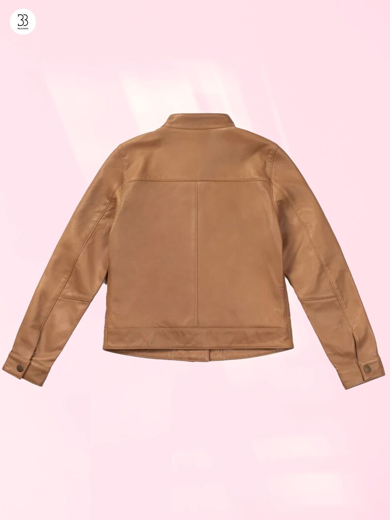 Puede incluir: Chaqueta de cuero color marr&oacute;n claro con un dise&ntilde;o cl&aacute;sico. La chaqueta presenta un cuello alzado, pu&ntilde;os abotonados y un corte entallado. La parte trasera de la chaqueta es visible, mostrando las costuras y los paneles. La chaqueta es de color neutro.