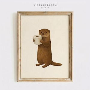 May include: A framed print featuring a brown otter holding a roll of white toilet paper. The otter is standing upright against a cream-colored background. The print has a vintage aesthetic, with the text "VINTAGE BLOOM PRINTS" at the top.