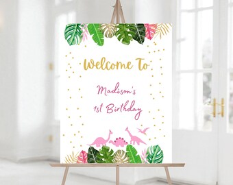 Puede incluir: Bienvenido al 1er cumpleaños de Madison, cartel con temática tropical. El cartel presenta dinosaurios rosas, hojas verdes y purpurina dorada.