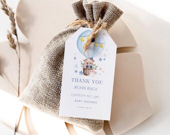 May include: A blue and white hot air balloon with a teddy bear inside. The balloon is surrounded by stars. The tag says "Thank You Bearly Much Elizabeth and Luke Baby Shower".