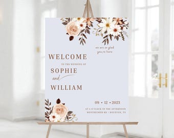 May include: A wedding welcome sign with a light blue background and floral design. The sign reads "Welcome to the wedding of Sophie and William" with the date "09.12.2023" and the time and location of the wedding.