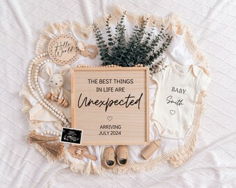 May include: A pregnancy announcement with a wooden sign that reads "The best things in life are unexpected" and "Arriving July 2024." Includes a baby onesie, ultrasound image, baby shoes, and a plush bunny.