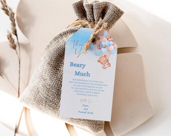 May include: A blue and white thank you tag with a teddy bear holding balloons. The tag says "Beary Much" and includes a message thanking guests for showering the couple with love and sharing in the celebration of their little bundle of joy. The tag is tied to a small burlap bag.