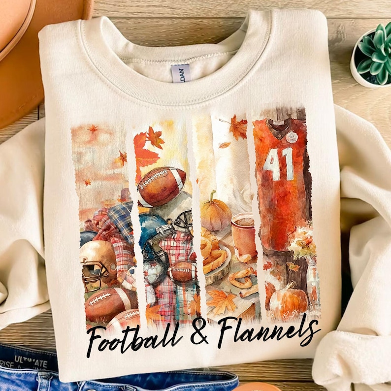 May include: Cream-colored sweatshirt with a graphic design featuring footballs, helmets, a jersey with the number 41, pumpkins, and fall leaves. The text "Football & Flannels" is printed at the bottom of the design.