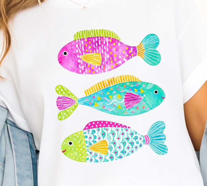 Op de afbeelding: Wit T-shirt met drie kleurrijke visillustraties. De vissen zijn geschilderd in roze, turquoise en groen, met gele vinnen. Elke vis heeft een uniek patroon, wat zorgt voor een speels en artistiek ontwerp.