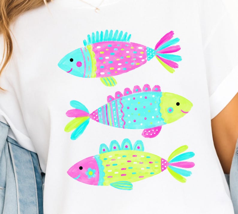 Op de afbeelding: Wit T-shirt met drie kleurrijke cartoonvissen. De vissen hebben roze, blauwe en gele lichamen met verschillende patronen en details. Elke vis heeft een lachend gezicht en een uniek vinontwerp. Een casual kledingstuk.
