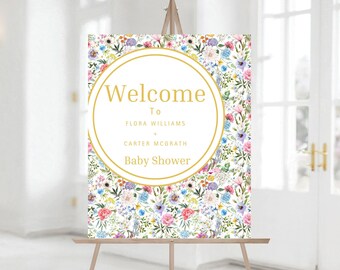 Op de afbeelding: Welkom bord voor de babyshower van Flora Williams en Carter McGrath met een bloemenpatroon in tinten roze, blauw, geel en groen. Het bord heeft een gouden cirkel met de tekst "Welcome to Flora Williams + Carter McGrath Baby Shower".