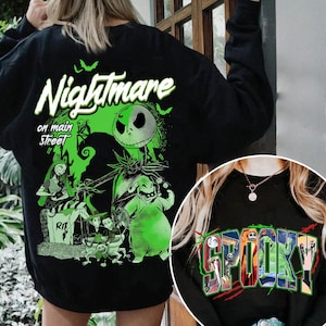 May include: Black sweatshirt featuring a green and white graphic from "The Nightmare Before Christmas." The design includes Jack Skellington, Sally, and other characters, with the text "Nightmare on Main Street." A smaller image shows the word "Spooky!"