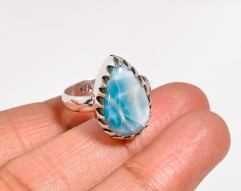 May include: A sterling silver ring featuring a pear-shaped, light blue gemstone with white marbling. The ring has a decorative bezel setting and a band stamped with "925". The gemstone is approximately 1 inch in length.