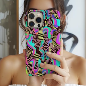 May include: A brightly coloured phone case with an abstract design. The case has a black background with wavy lines in neon shades of pink, green, yellow, and blue. The phone case is held up in front of a person.