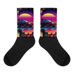 May include: A pair of black socks with a retro 80s design featuring a sunset, palm trees, and a car. The socks have a colourful design with pink, purple, blue, and yellow.