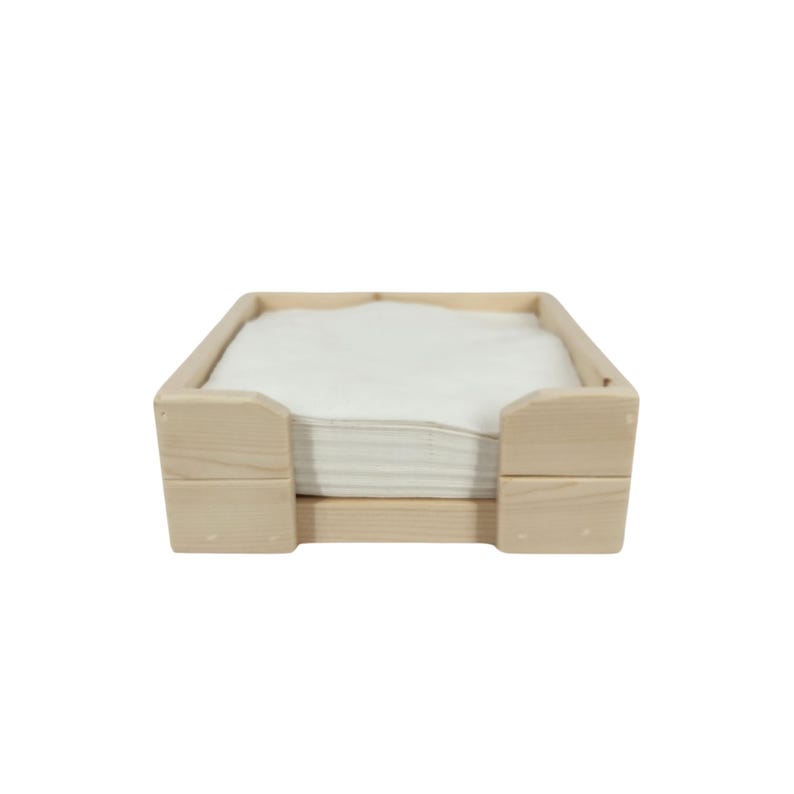 May include: A wooden napkin holder with a stack of white napkins inside. The holder is made of natural wood and has a simple, rustic design.