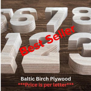 A collection of three-dimensional numbers crafted from light-colored wood with visible grain patterns. The numbers are arranged in a group, showcasing their thick, layered plywood construction and smooth, flat surfaces.