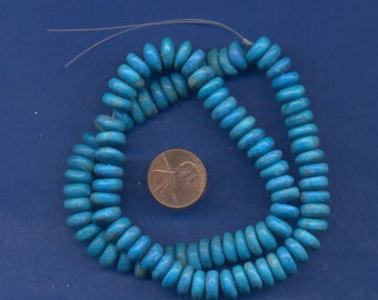 May include: A strand of turquoise-colored, disc-shaped beads. The beads are a vibrant blue with lighter blue marbling. A U.S. penny is next to the beads for size comparison. The beads are strung on a clear, thin cord, ready for jewelry making.
