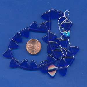 May include: A strand of cobalt blue glass triangle beads. The beads are approximately the size of a US penny.