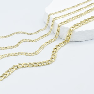 May include: Four gold chains of different thicknesses, laid out on a white surface.